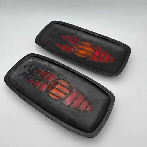A Set Of Two Rectangular Black Ceramic Dishes, Each Decorated With A Stylized Fi